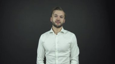 Beyaz gömlekli şaşkın adam düzgün görünüyor ve gülümsüyor.