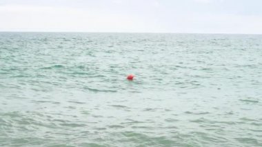 Çöl denizinde kırmızı bir şamandıra yavaş çekimde sallanıyor.