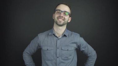 Yakışıklı adam gülümseyerek kalçalarıyla el ele tutuşup poz veriyor.