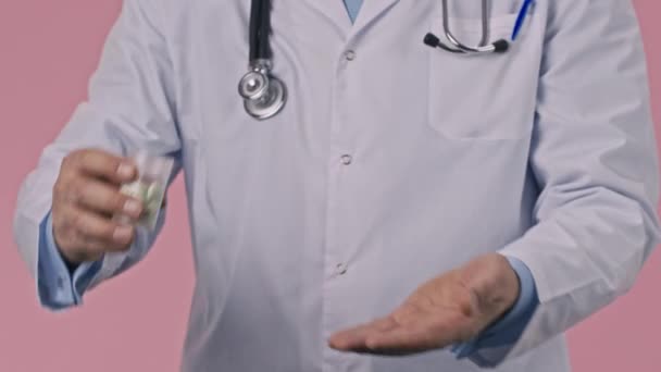 Close up médico em uniforme médico derramando todos os comprimidos para baixo, segurando-os na palma da mão — Vídeo de Stock