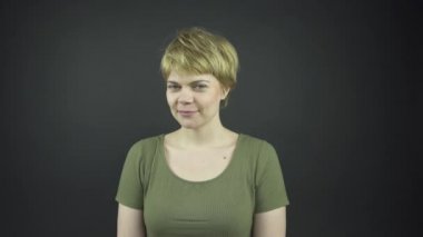 Yeşil tişörtlü şık bayan etrafına bakar ve yüzüne dokunur.