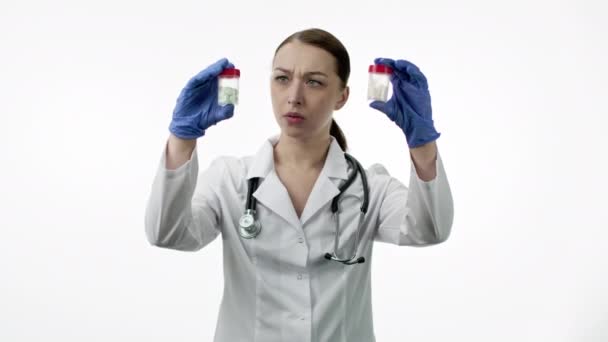 Inexperienced concentrated nurse compares two jars with pills, patient treatment — Stock Video