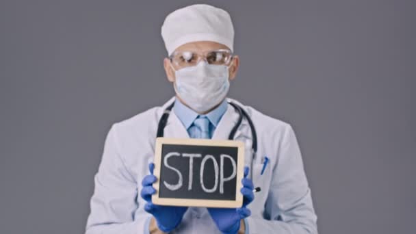 Lab technicus in beschermend masker tablet met stop teken in handen — Stockvideo