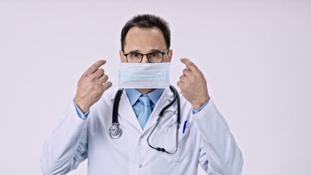 Knappe mannelijke arts zet beschermende masker tegen covid-19 virus en bacteriën — Stockvideo