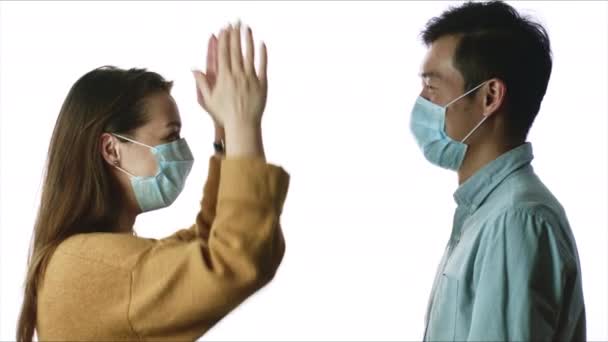 Deux personnes interracial, femme caucasienne et homme asiatique en masques médicaux parlent — Video