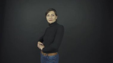 Siyah kazaklı ve kot pantolonlu harika bir kadın poz veriyor.