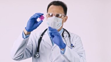 Koruyucu maskeli yakışıklı laboratuvar teknisyeni covid-19 virüs hücresini araştırıyor.
