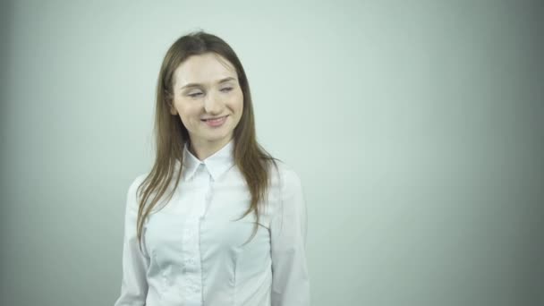 Fashionable girl in white blouse fixes flowing hair by wall — Stock Video