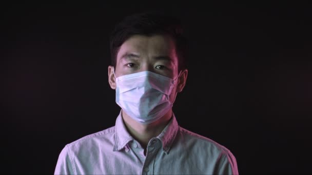 Aziatische man zet medische masker tegen covid-19 en haalt diep adem — Stockvideo