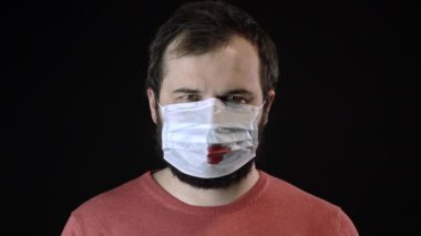 Üzerinde kan olan maskeli hasta adam yeni bir maske takıyor. Covid-19 konsepti