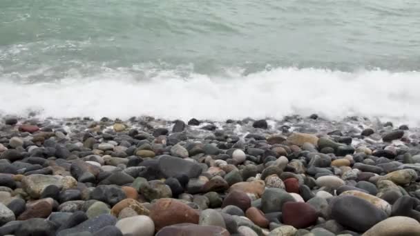 Морские волны катятся по галечному берегу во время небольшой бури вблизи — стоковое видео