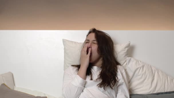 Κουρασμένη όμορφη νεαρή γυναίκα χασμουριέται, φοράει μάσκα ύπνου και κοιμάται — Αρχείο Βίντεο