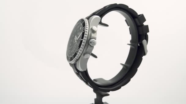 瑞士伊巴赫2020年4月7日-维多利亚牛人手表不锈钢外壳黑钟表盘橡胶表带在白色背景隔离的支架上转动 — 图库视频影像