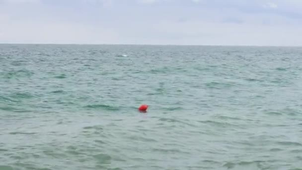 Een rode boei op een woestijn zee zwaaiend op de golven — Stockvideo