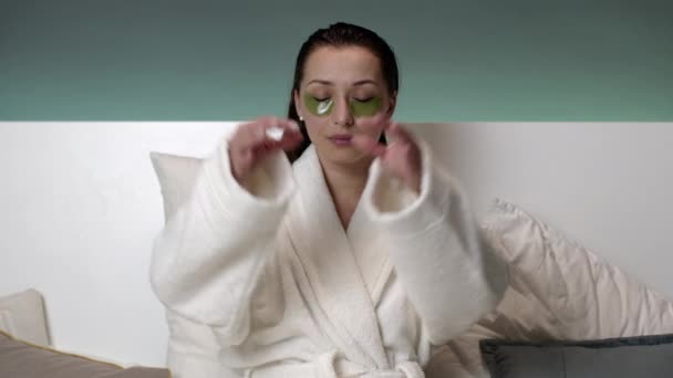 Schöne Frau mit Pflaster im Gesicht meditiert vor dem Schlafengehen im Bett. — Stockvideo