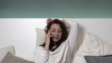 Beyaz gecelikli seksi kahverengi saçlı kız yatmadan önce iletişim kuruyor.