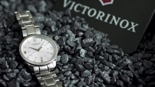 Ібах, Швейцарія 7.04.2020 - Вікторінокс Людина спостерігає за білим годинником з нержавіючої сталі на циферблаті з нержавіючої сталі, який лежить на сірих камінцях. — стокове відео
