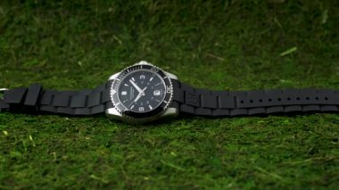İbach, İsviçre 7.04.2020 - Victorinox Man paslanmaz çelik kasa siyah saat yüz çevirmeli lastik kayış yeşil yosun üzerinde yatıyor