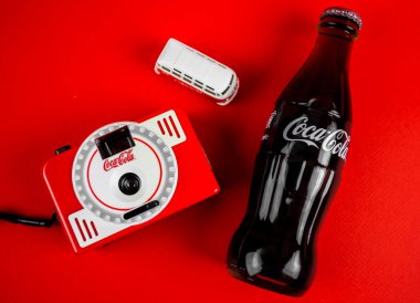 Atlanta, Georgia, ABD 1 Nisan 2020: Coca-Cola kontur şişesi, markalı kamera, Vintage ölüm oyuncağı kırmızı arka planda izole edilmiş