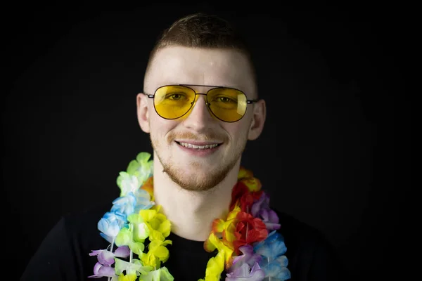 Happy young man wearing Hawaiian welcome necklace looks at camera in sunglasses — Stock Photo, Image