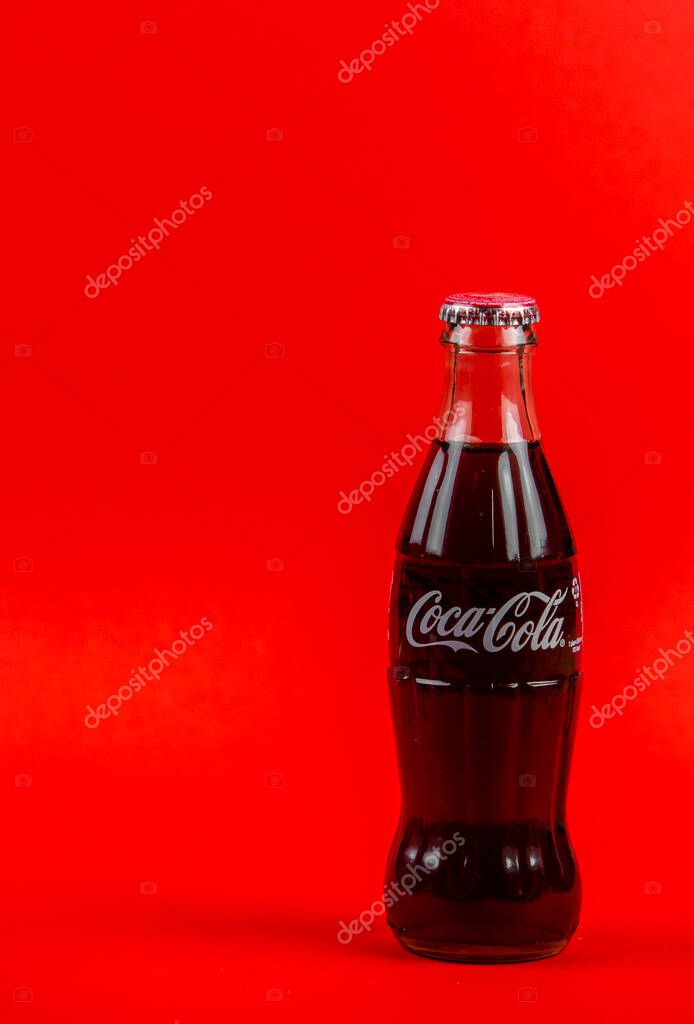 Atlanta, Georgia, USA April 1, 2020: closeup of classic contour glass bottle of Coca Cola white logo from USA isolated on red background. concept of globalism, global brand, worldwide spread.