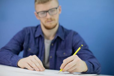 Mavi arkaplanda kalemle izole edilmiş düşünceli genç tasarımcı çizimleri