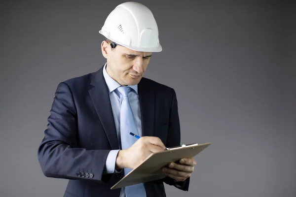 Вдумчивый красивый строитель нефтяник в белом шлеме пишет на планшете — стоковое фото