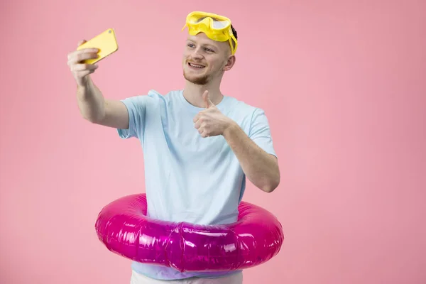 Glücklich gestikulierender junger Geschäftsmann im aufblasbaren Schwimmring, der Selfies macht — Stockfoto