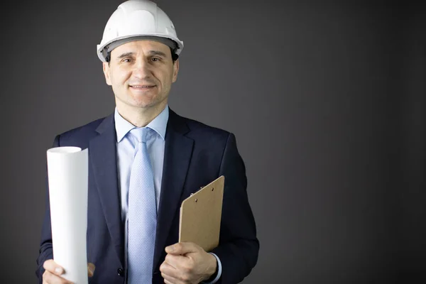 Positieve knappe constructeur in helm formele kleding houdt tekening lachend — Stockfoto