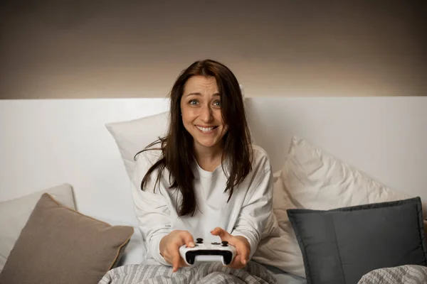 Sourire fille drôle joue à des jeux vidéo sur la console avec excitation avant de dormir — Photo