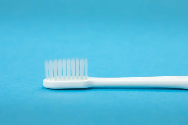 Enkele witte tandenborstel close-up geïsoleerd op blauwe achtergrond horizontaal — Stockfoto