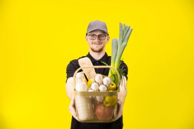 Siyah üniformalı kurye alışveriş sepetini tutuyor, teslimatçıya odaklan.