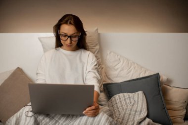 Seksi iş kadını dizüstü bilgisayarla yatakta, gece geç saatlere kadar çalışıyor.