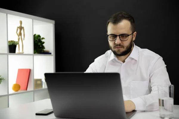 Joven hombre de negocios guapo que trabaja en la computadora en la oficina en casa, hace videollamada — Foto de Stock