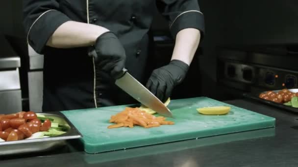 Kookt handen in zwarte handschoenen snijden gele paprika — Stockvideo