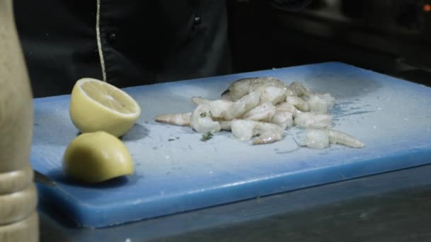 Faire cuire une salade de crevettes, arroser les crevettes avec du jus de citron pressé, ajouter de l'huile d'olive, poivre noir, gros sel de mer, graines de sésame, décorer la salade avec des herbes. gros plan — Video