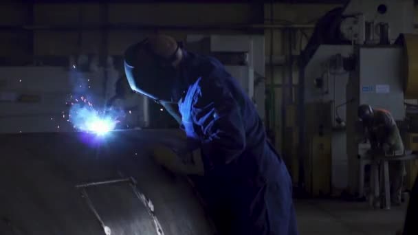 Svářečka s ochrannou maskou a rukavicemi svařuje trubku o velkém průměru v průmyslové dílně — Stock video