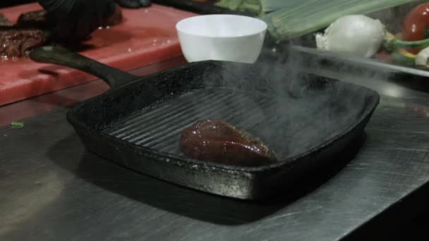 Šéfkuchař dává hovězí steaky do pánve na grilování. zavřít selektivní zaměření — Stock video