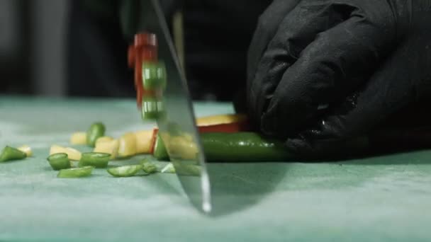 Cooks hands in black gloves slicing chili peppers close up selective focus — Stock Video