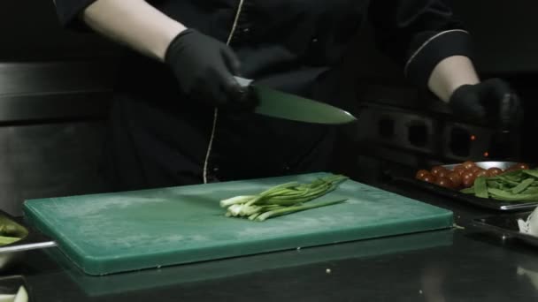 Cozinheiros mãos em luvas pretas cortando cebolas verdes — Vídeo de Stock