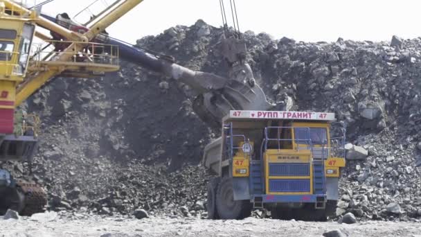 Mikashevichi, Belarus, 14.04.2020 - Large excavator loading granite into heavy dump truck Belaz — Stock Video