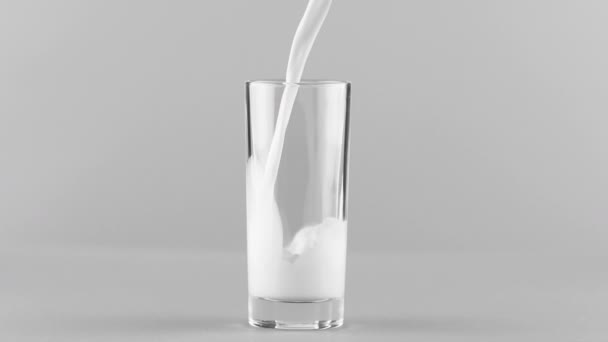 Milk pouring into glass close up isolated on light grey background Slow motion — Stock Video