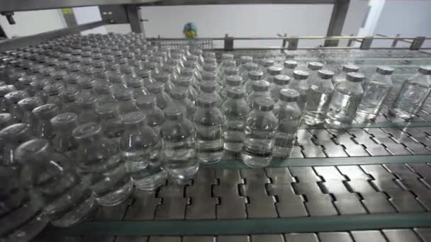 Tıbbi çözüm konveyör hattında plastik ve alüminyum kapaklarla doldurulmuş ve mühürlenmiş cam şişeler. — Stok video