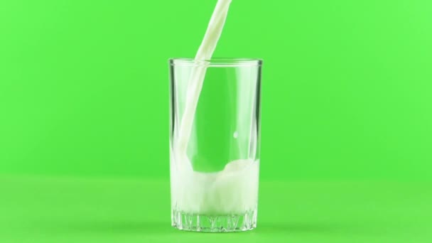 Melk gieten in glas close-up geïsoleerd op licht groene achtergrond Slow motion — Stockvideo