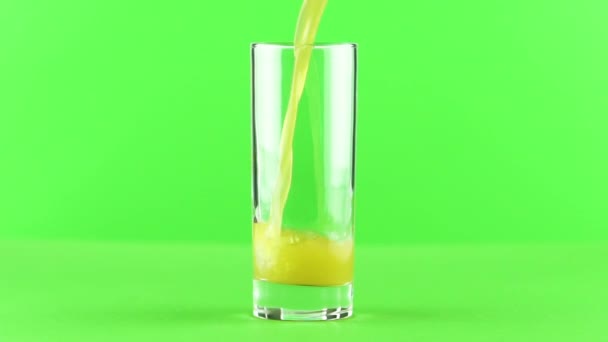 Сок наливается в стекло изолированы на светло-зеленом фоне замедленного движения — стоковое видео