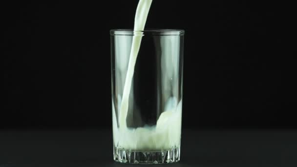 Melk gieten in glas close-up geïsoleerd op zwarte achtergrond Slow motion — Stockvideo