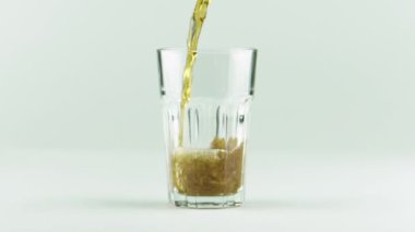 Kola, baloncuk ve köpüklerle dolu, beyaz arka planda ağır çekimde izole edilmiş bir bardağa dökülür.