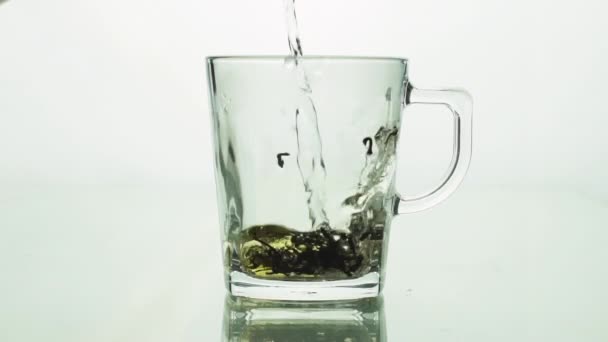 particules de thé noir verser dans une tasse transparente en verre et rempli d'eau bouillante pour infuser le thé isolé sur fond blanc ralenti fermer 