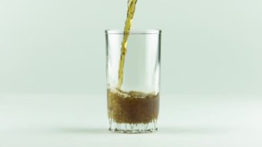 Kola, baloncuk ve köpüklerle dolu bir bardağa doldurulur. Beyaz arka planda yavaş çekimde izole edilir.