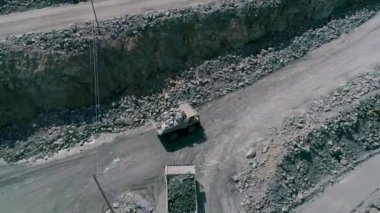Büyük granit açık maden ocağında maden kamyonları. Yüklü kamyonlar taş ocağı insansız hava aracı takibi manzarasında